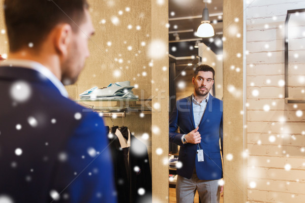 man trying jacket on at mirror in clothing store Stock photo © dolgachov