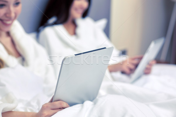 happy women in bathrobes with tablet pc at hotel Stock photo © dolgachov