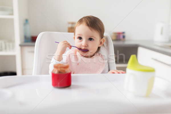 baby girl with spoon eating puree from jar at home Stock photo © dolgachov