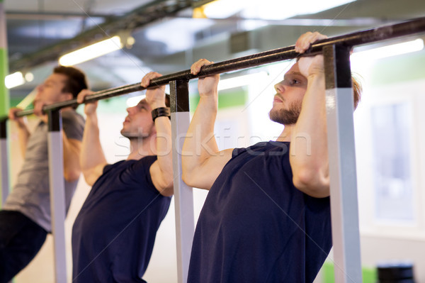 group of young men doing pull-ups in gym Stock photo © dolgachov