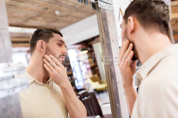 man looking at himself at barbershop mirror Stock photo © dolgachov