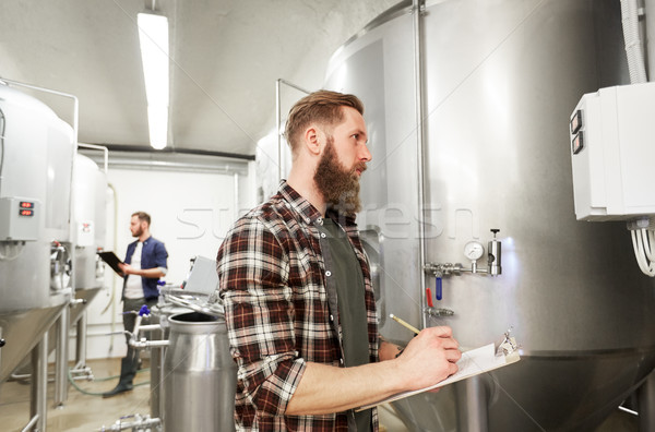 men with clipboard at craft brewery or beer plant Stock photo © dolgachov