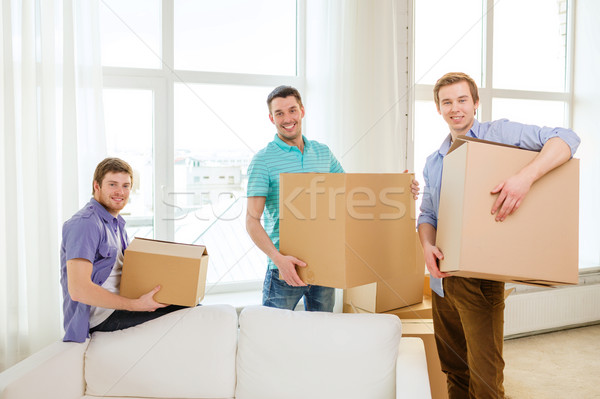 smiling male friends carrying boxes at new place Stock photo © dolgachov