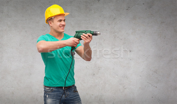 smiling manual worker in helmet with drill machine Stock photo © dolgachov