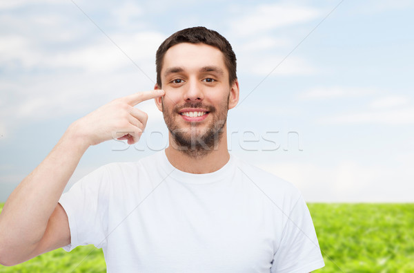 smiling young handsome man pointing to eyes Stock photo © dolgachov