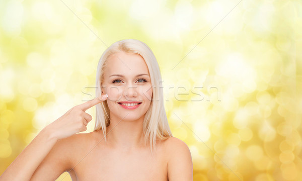 smiling young woman pointing at her cheek Stock photo © dolgachov