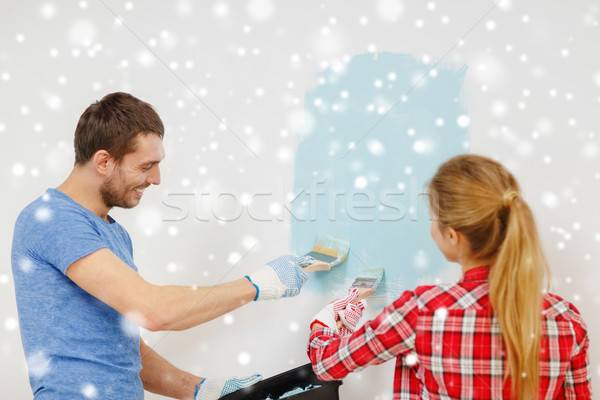 smiling couple with paintbrushes painting wall Stock photo © dolgachov