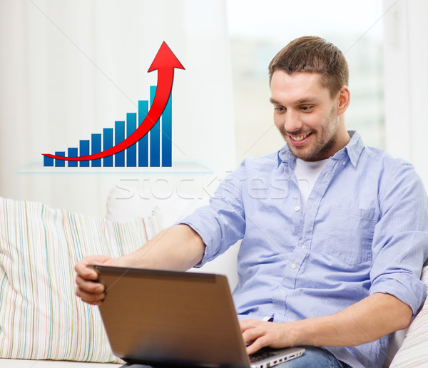 Stock photo: smiling man with laptop and growth chart at home