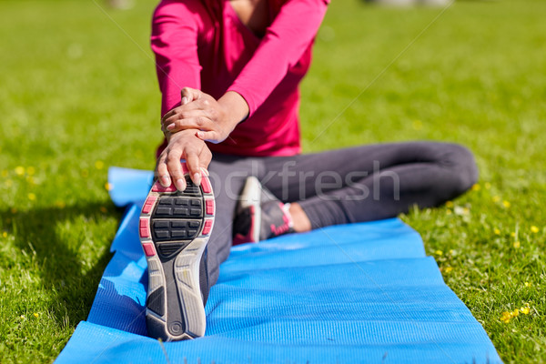 close up of woman stretching leg on mat outdoors Stock photo © dolgachov