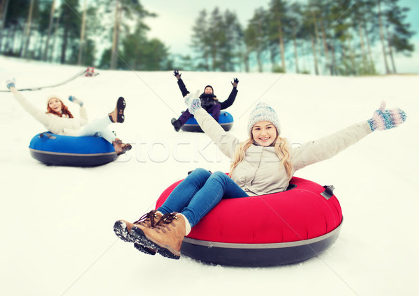 Stock photo: group of happy friends sliding down on snow tubes
