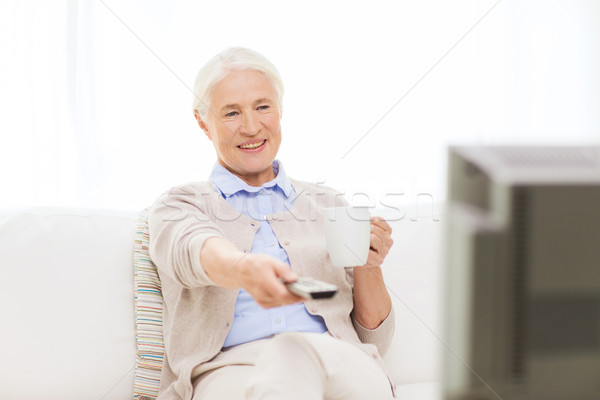senior woman watching tv and drinking tea at home Stock photo © dolgachov