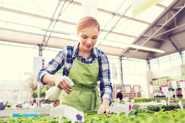 Stock photo: woman with sprayer and seedling in greenhouse