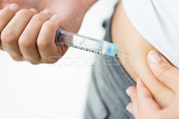 Stock photo: close up of hands making injection by insulin pen