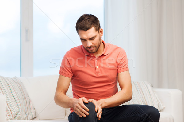 unhappy man suffering from pain in leg at home Stock photo © dolgachov