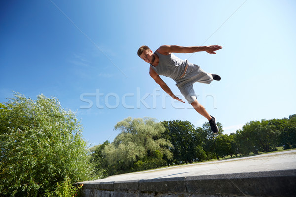 sporty young man jumping in summer park Stock photo © dolgachov