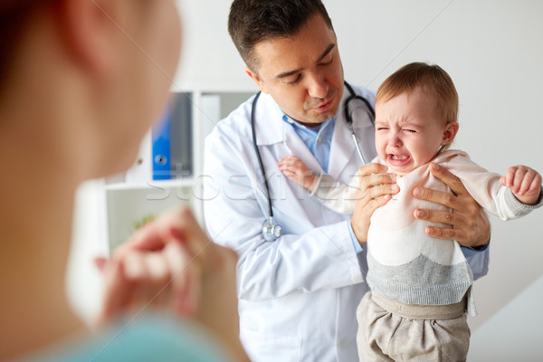 doctor or pediatrician with crying baby at clinic Stock photo © dolgachov