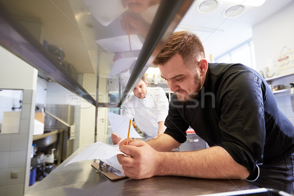 chef and cook with lists or bills at kitchen Stock photo © dolgachov