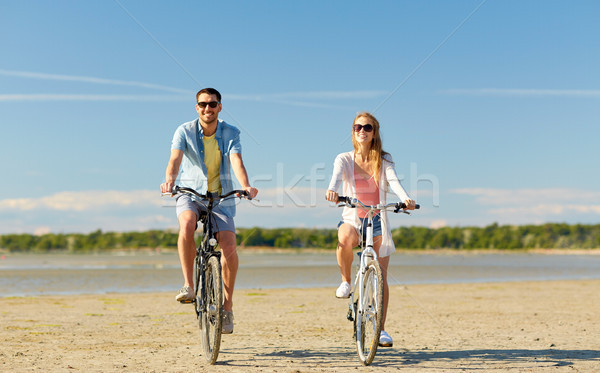 happy young couple riding bicycles at seaside Stock photo © dolgachov