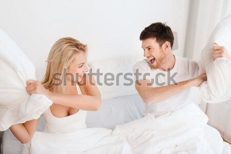 Heureux couple bataille d'oreillers lit maison personnes [[stock_photo]] © dolgachov