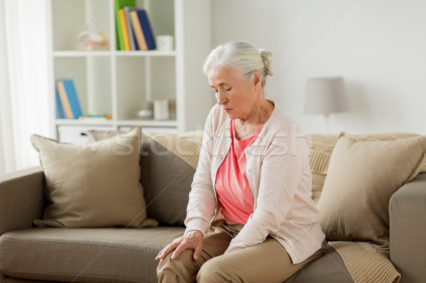 senior woman suffering from pain in leg at home Stock photo © dolgachov