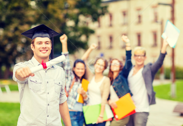smiling teenage boy in corner-cap with diploma Stock photo © dolgachov