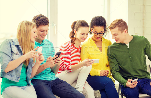 smiling students with smartphone texting at school Stock photo © dolgachov