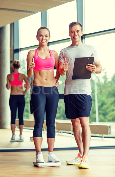 smiling man and woman with scales in gym Stock photo © dolgachov
