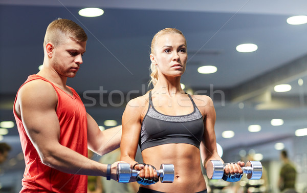 young couple with dumbbells flexing muscles in gym Stock photo © dolgachov