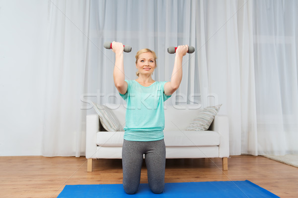 woman exercising with dumbbells on mat at home Stock photo © dolgachov
