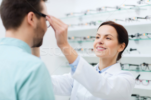 optician putting on glasses to man at optics store Stock photo © dolgachov