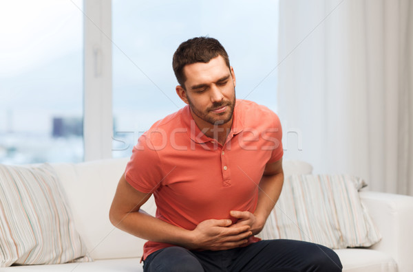 Stock photo: unhappy man suffering from stomach ache at home
