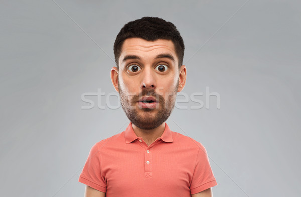 Stock photo: surprised man in polo t-shirt over gray background
