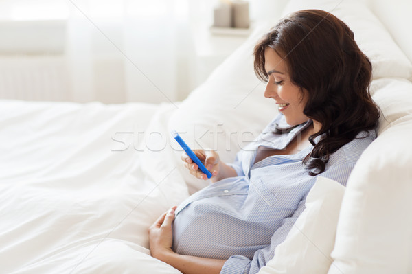 Fericit femeie gravida smartphone acasă pat sarcină Imagine de stoc © dolgachov