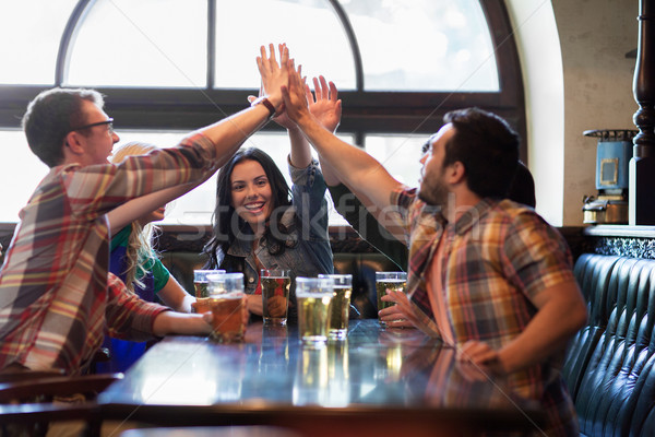 happy friends with beer making high five at pub Stock photo © dolgachov