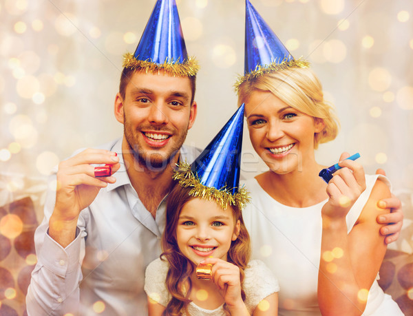 smiling family in blue hats blowing favor horns Stock photo © dolgachov