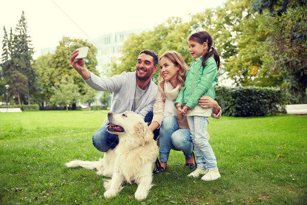 Stock photo: happy family with dog taking selfie by smartphone