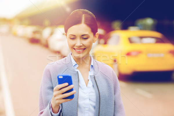 smiling woman with smartphone over taxi in city Stock photo © dolgachov