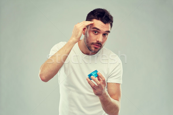happy young man styling his hair with wax or gel Stock photo © dolgachov