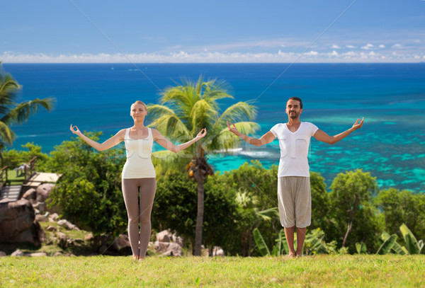 happy couple making yoga exercises on beach Stock photo © dolgachov