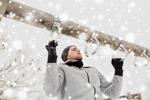 young man exercising on horizontal bar in winter Stock photo © dolgachov