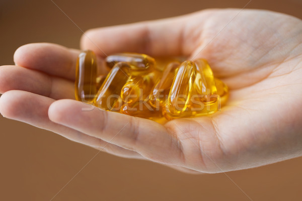 Kéz tart máj olaj kapszulák gyógyszer Stock fotó © dolgachov