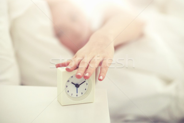 close up of woman with alarm clock in bed at home Stock photo © dolgachov