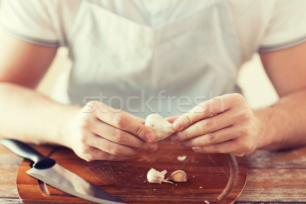 male hands taking off peel of garlic on board Stock photo © dolgachov