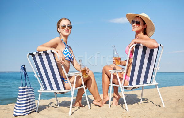 happy women sunbathing in lounges on beach Stock photo © dolgachov