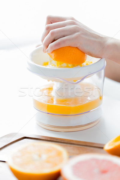 woman with squeezer squeezing orange juice at home Stock photo © dolgachov