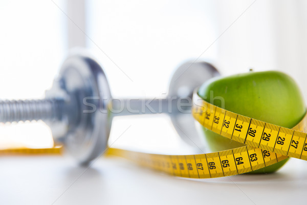 close up of dumbbell and apple with measuring tape Stock photo © dolgachov