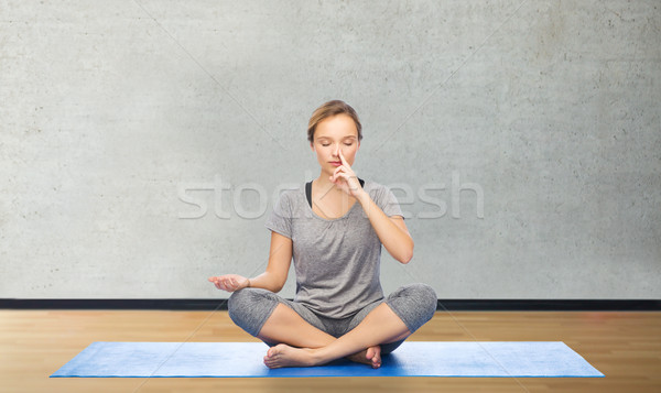 woman making yoga meditation in lotus pose on mat Stock photo © dolgachov