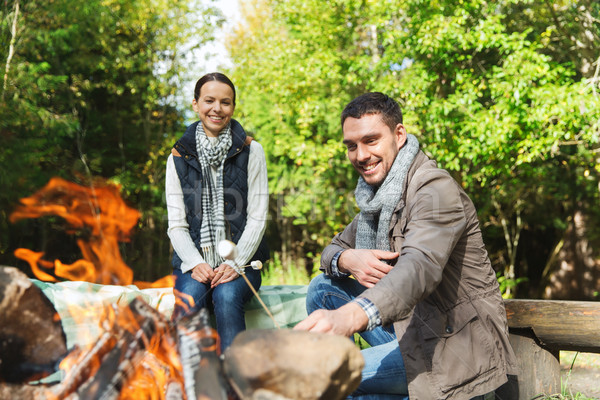 happy couple roasting marshmallow over camp fire Stock photo © dolgachov