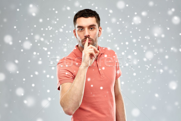 Stock photo: young man making hush sign over snow background