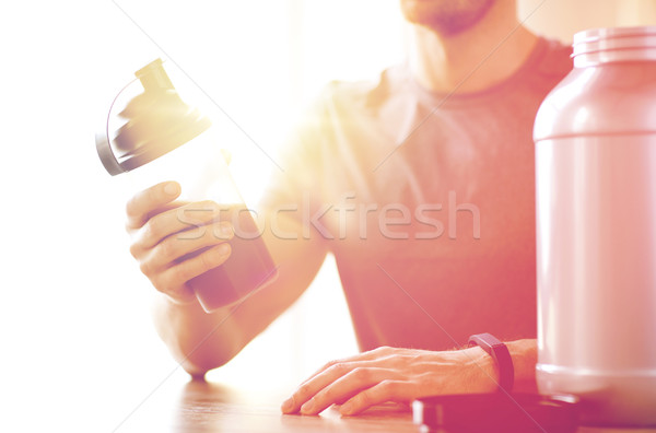 close up of man with protein shake bottle and jar Stock photo © dolgachov